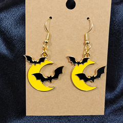 Woman wearing bat and moon enamel drop earrings