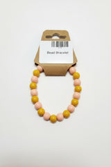 Mustard yellow and blush pink bead stretch bracelet on display card