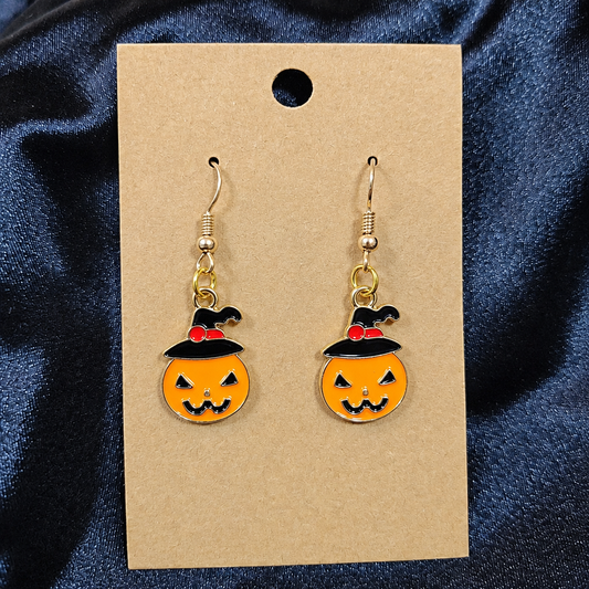 Woman wearing witch hat pumpkin enamel drop earrings