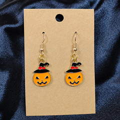 Woman wearing witch hat pumpkin enamel drop earrings
