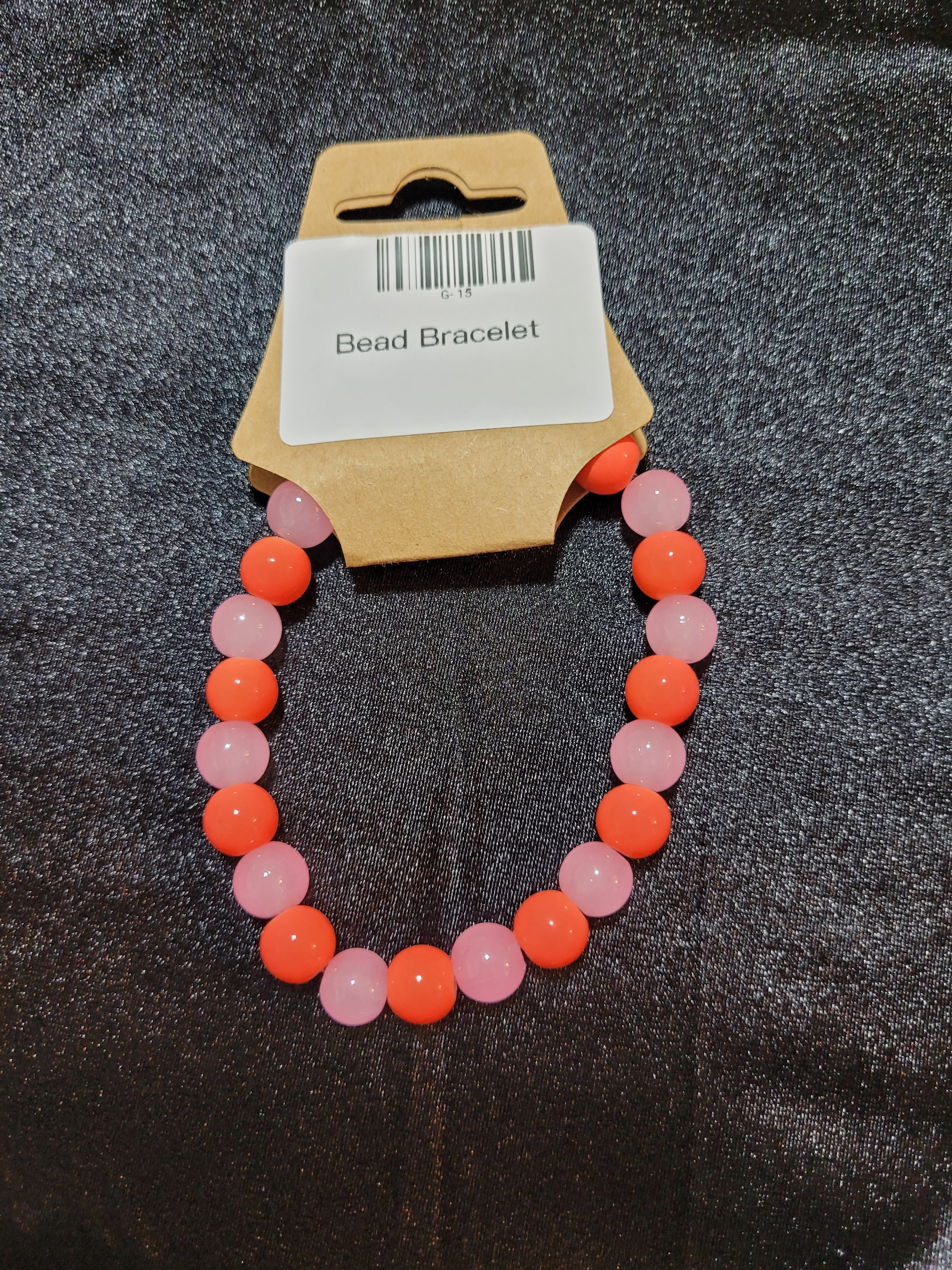 Coral orange and soft pink bead stretch bracelet on display card