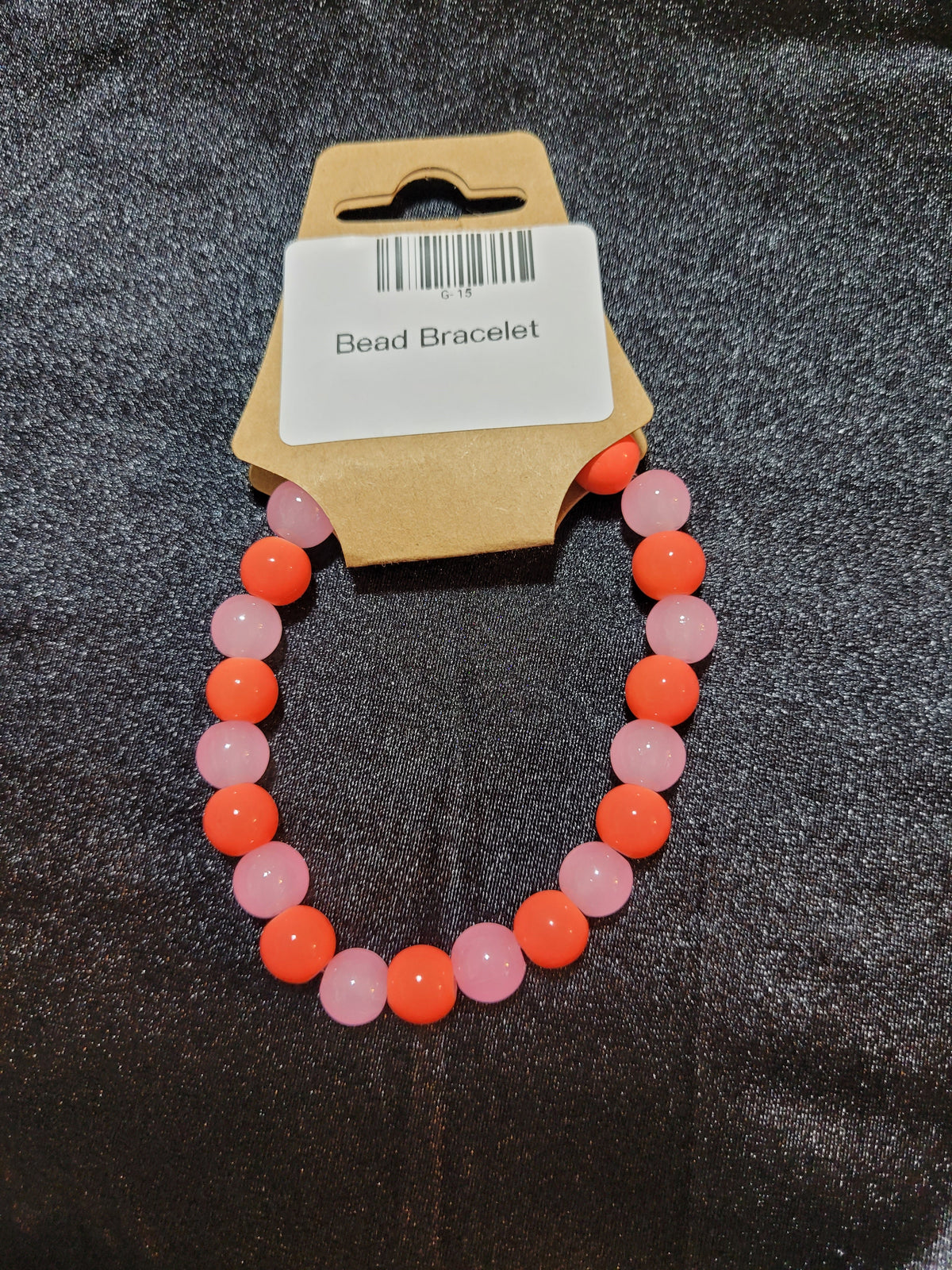 Coral orange and soft pink bead stretch bracelet on display card
