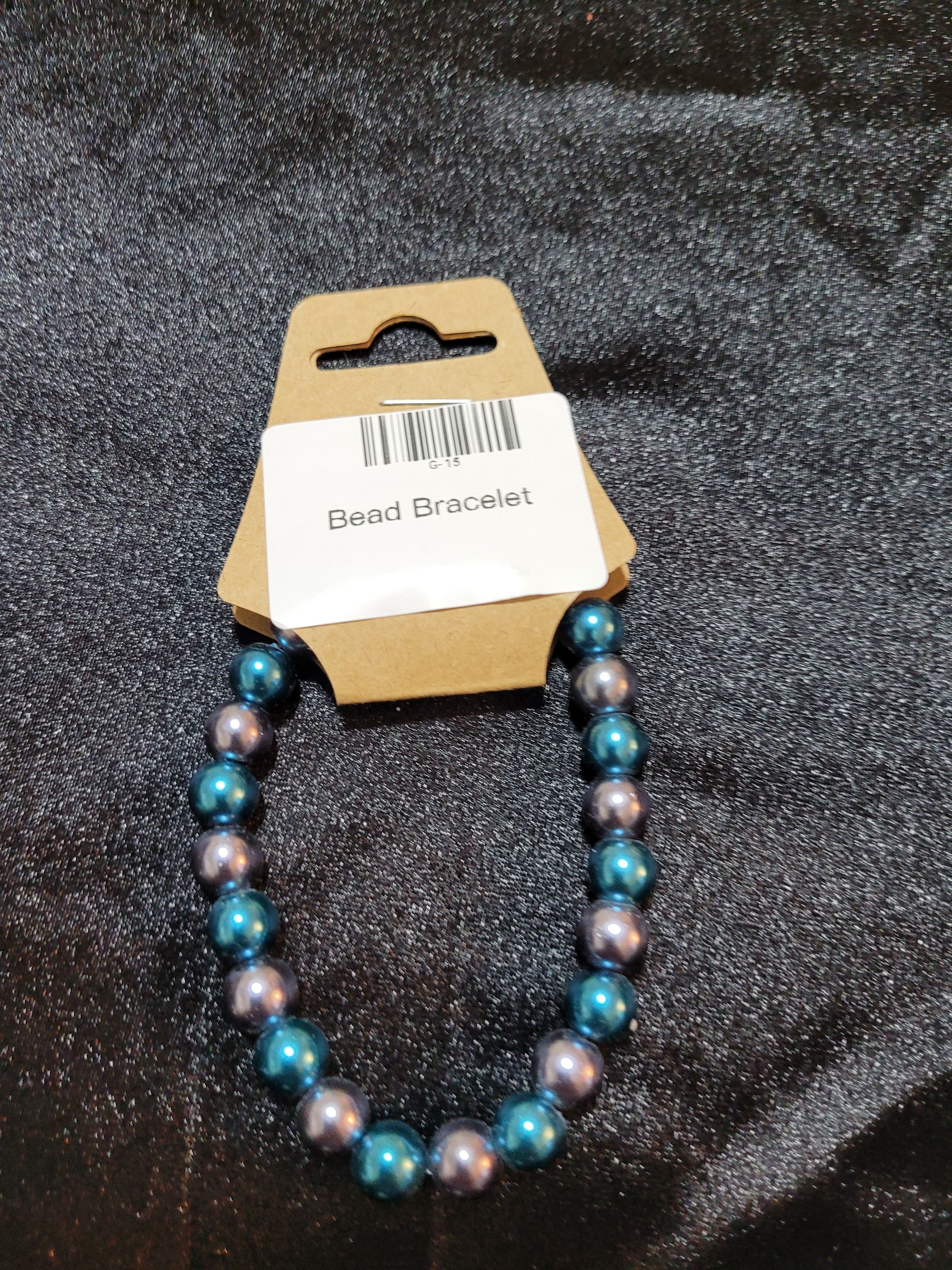 Teal and silver metallic bead stretch bracelet on display card