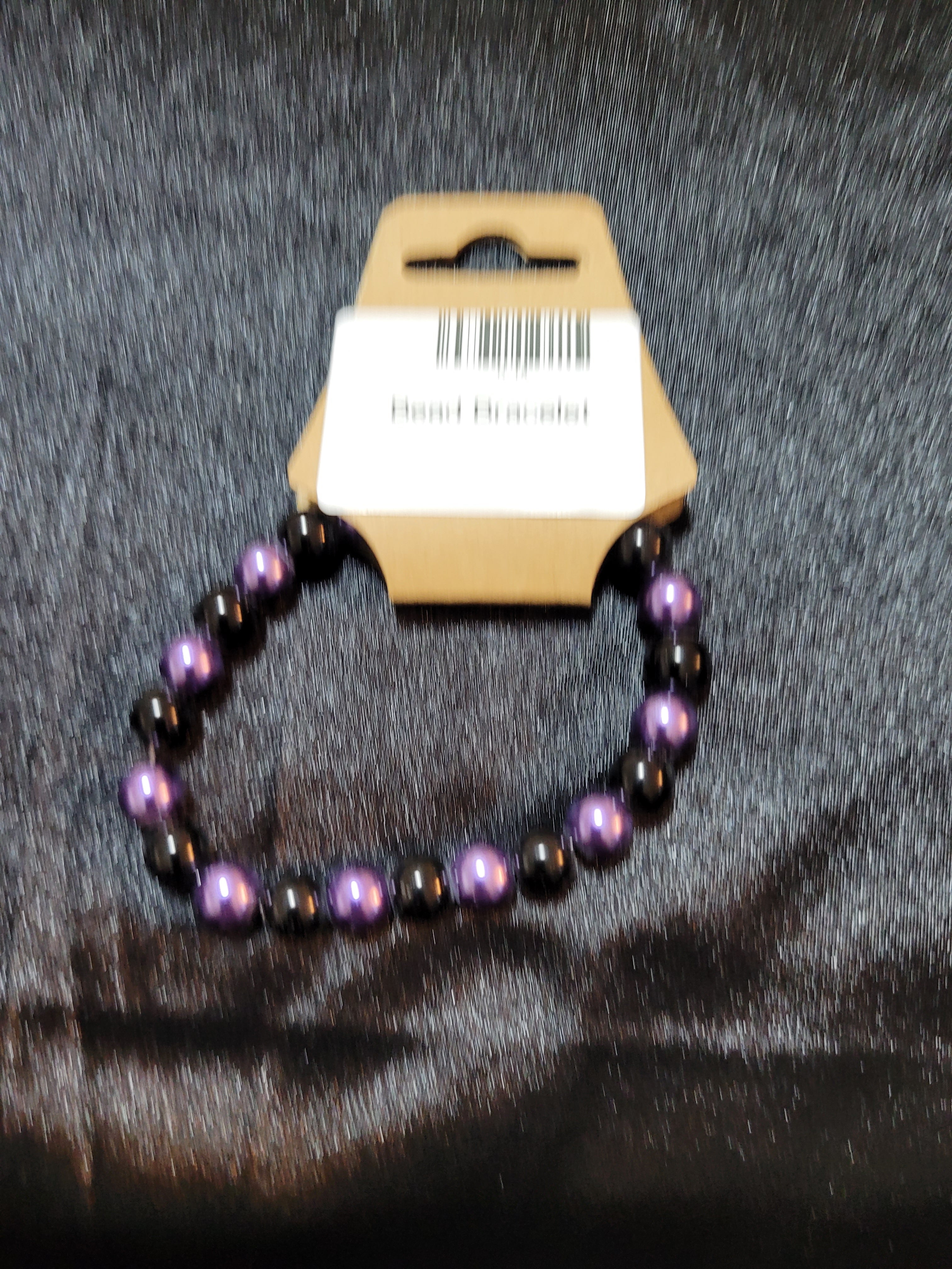 Purple and black metallic bead stretch bracelet on display card