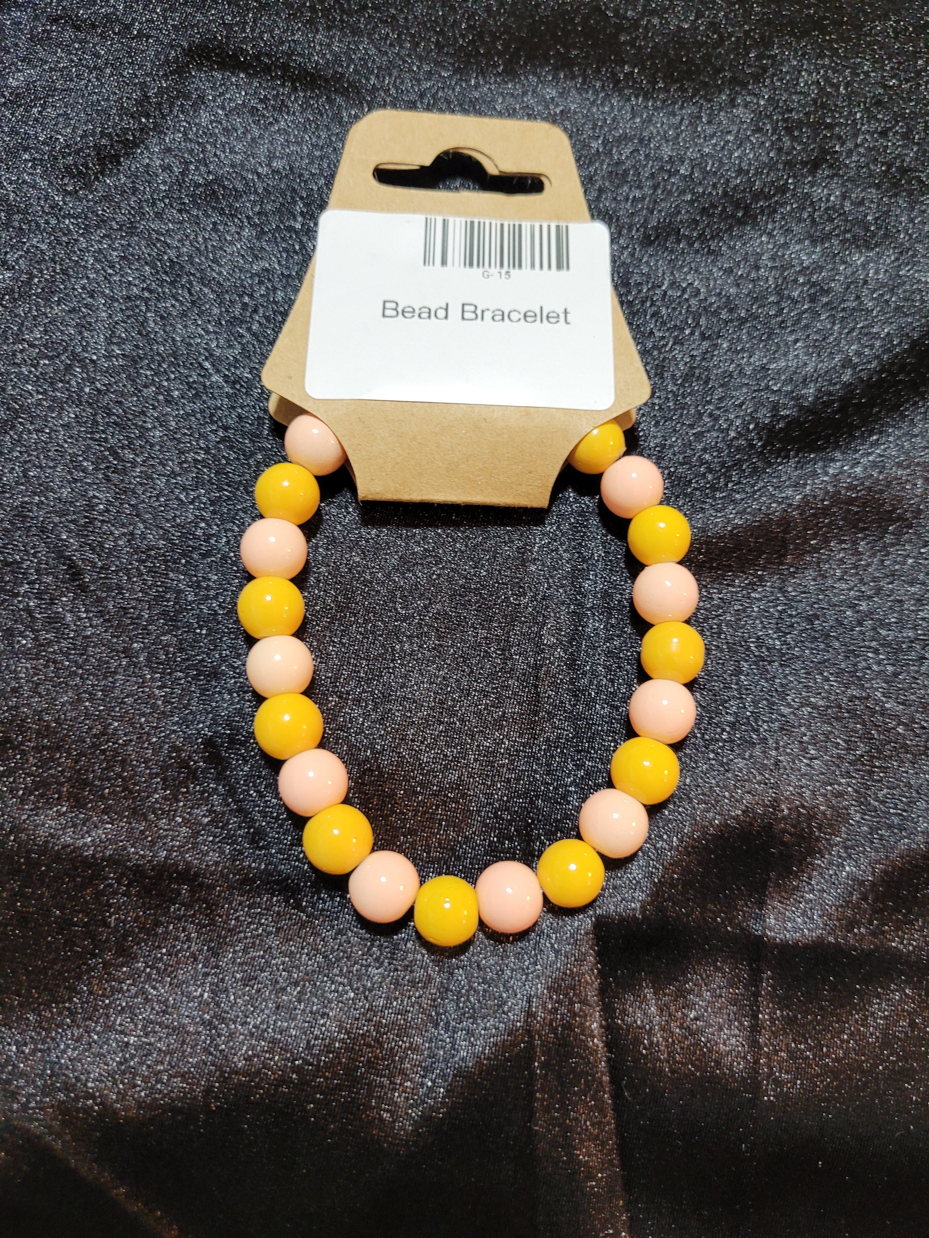 Mustard yellow and blush pink bead stretch bracelet on display card