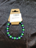 Metallic green and navy blue bead stretch bracelet on display card