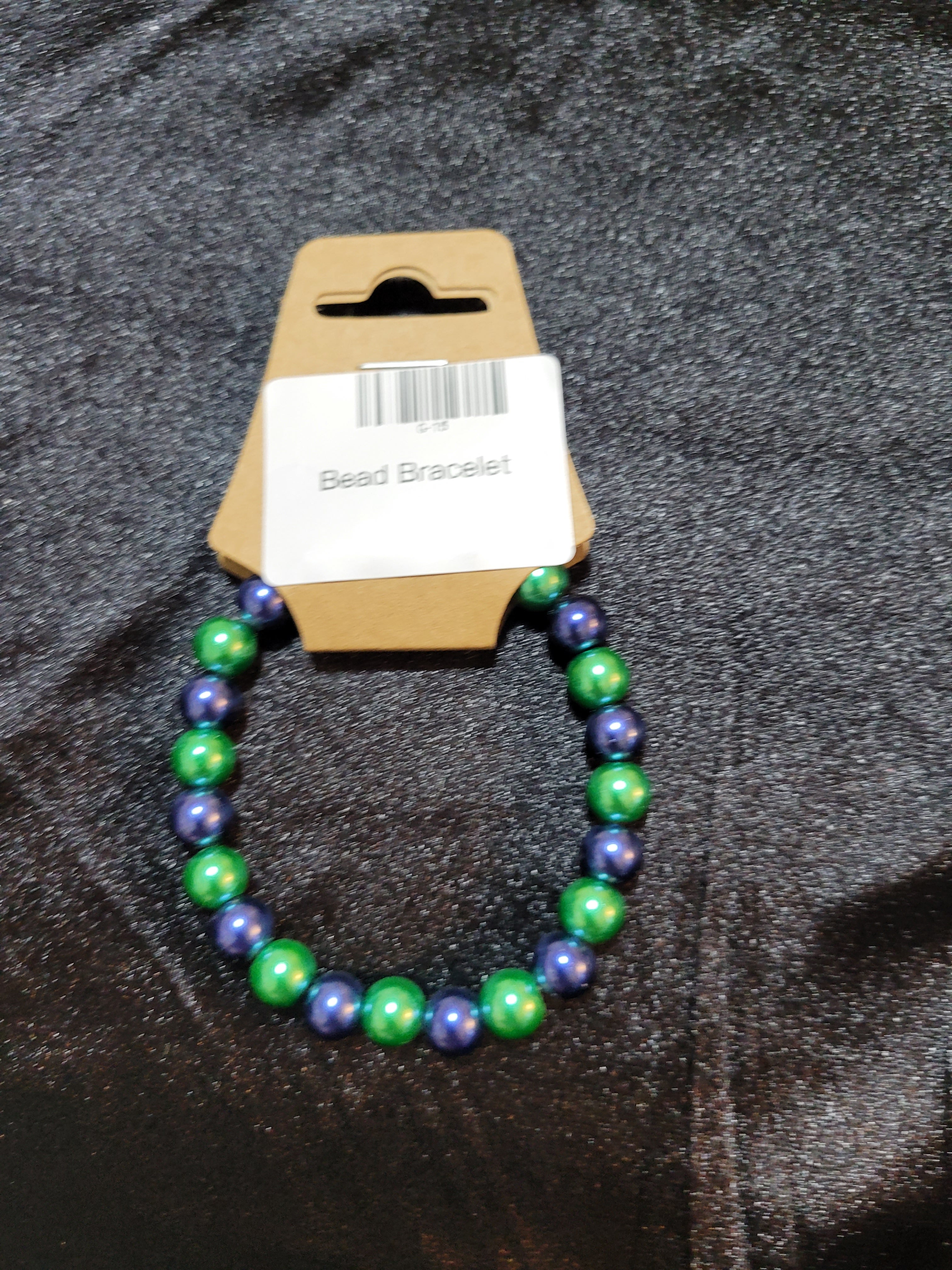 Metallic green and navy blue bead stretch bracelet on display card