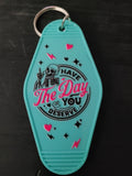 Have The Day You Deserve teal motel-style keychain with skeleton and pink hearts