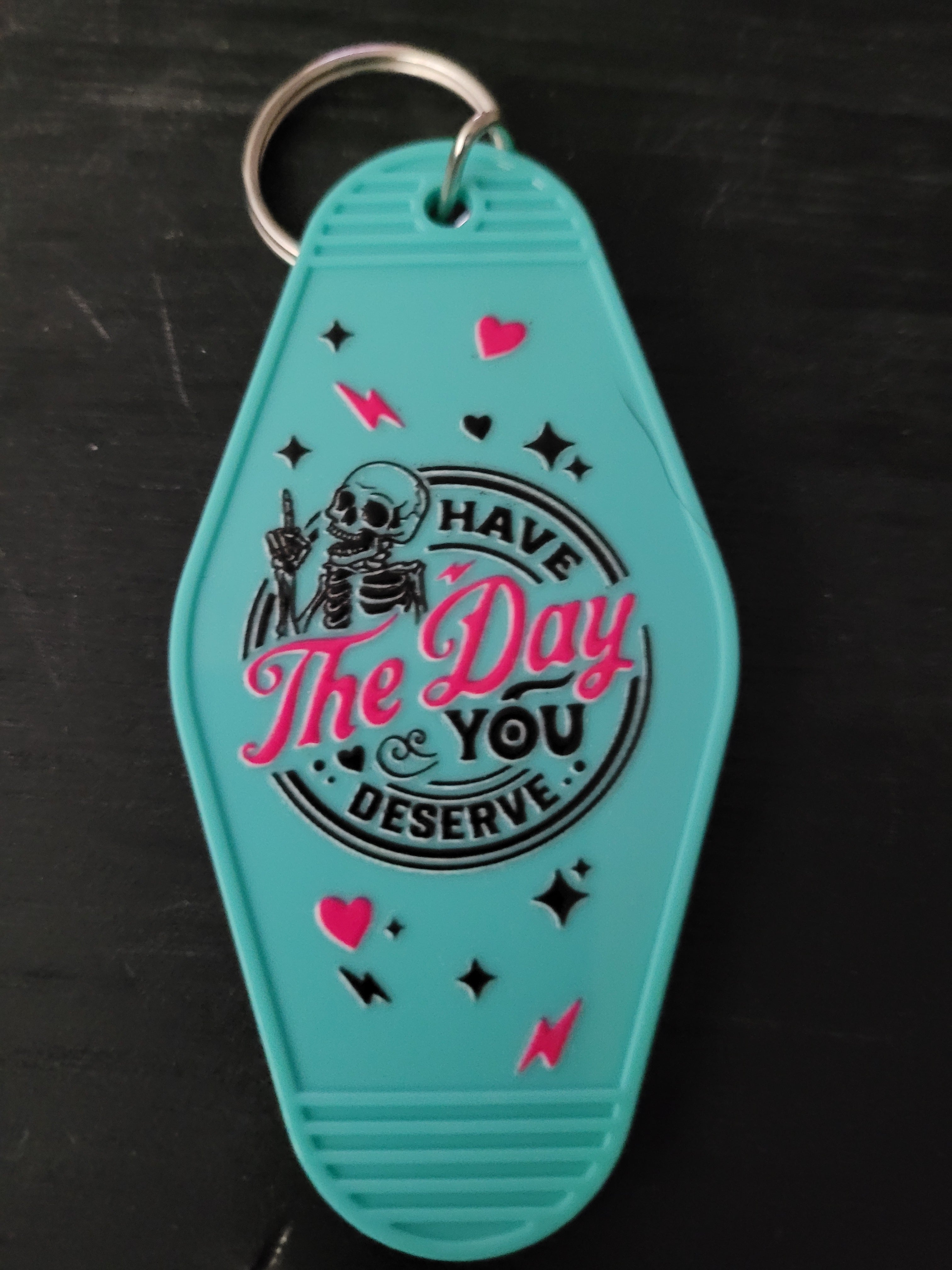 Have The Day You Deserve teal motel-style keychain with skeleton and pink hearts
