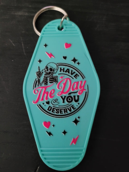 Have The Day You Deserve teal motel-style keychain with skeleton and pink hearts