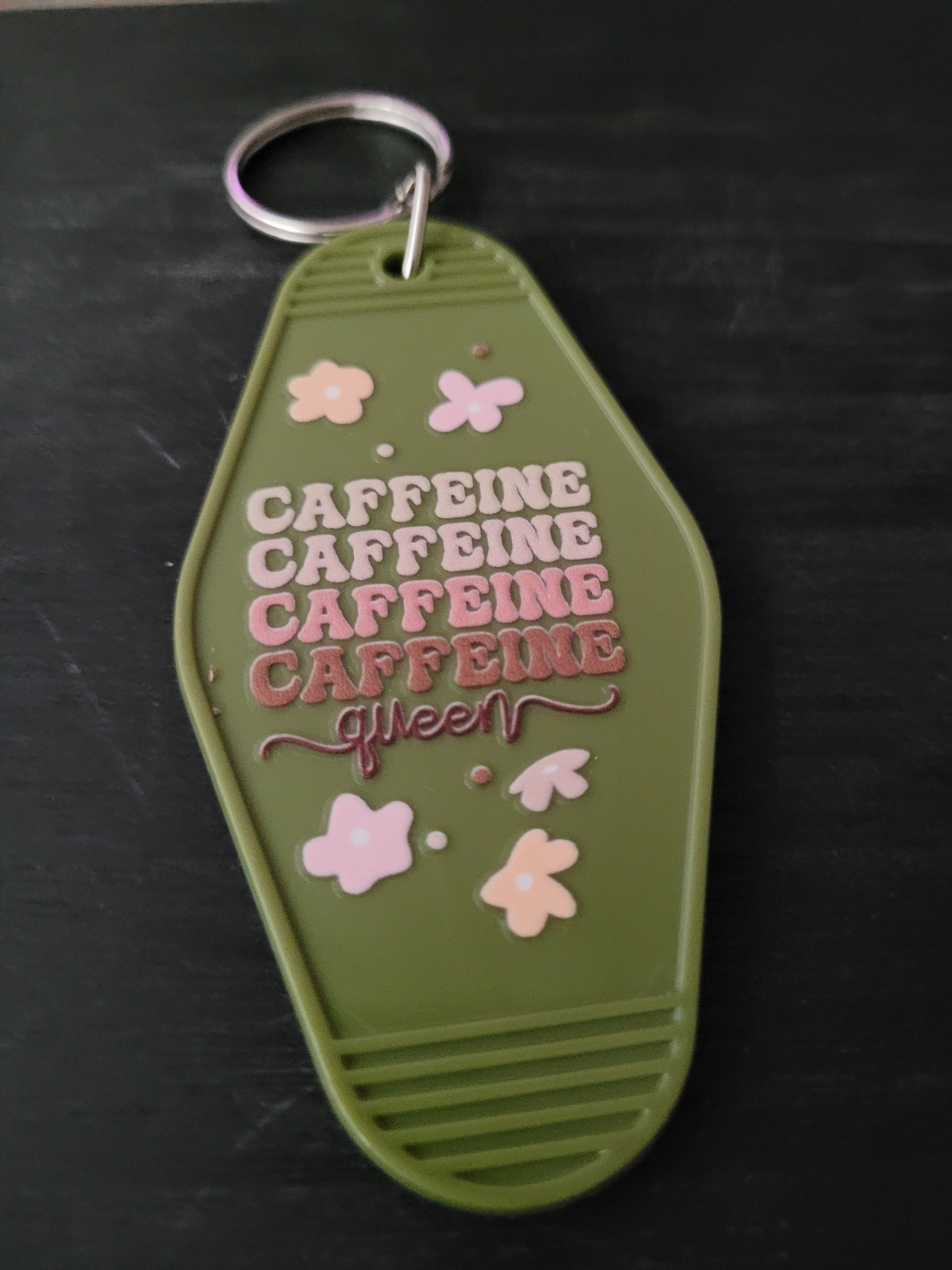 Caffeine Queen olive green motel-style keychain with pink floral accents