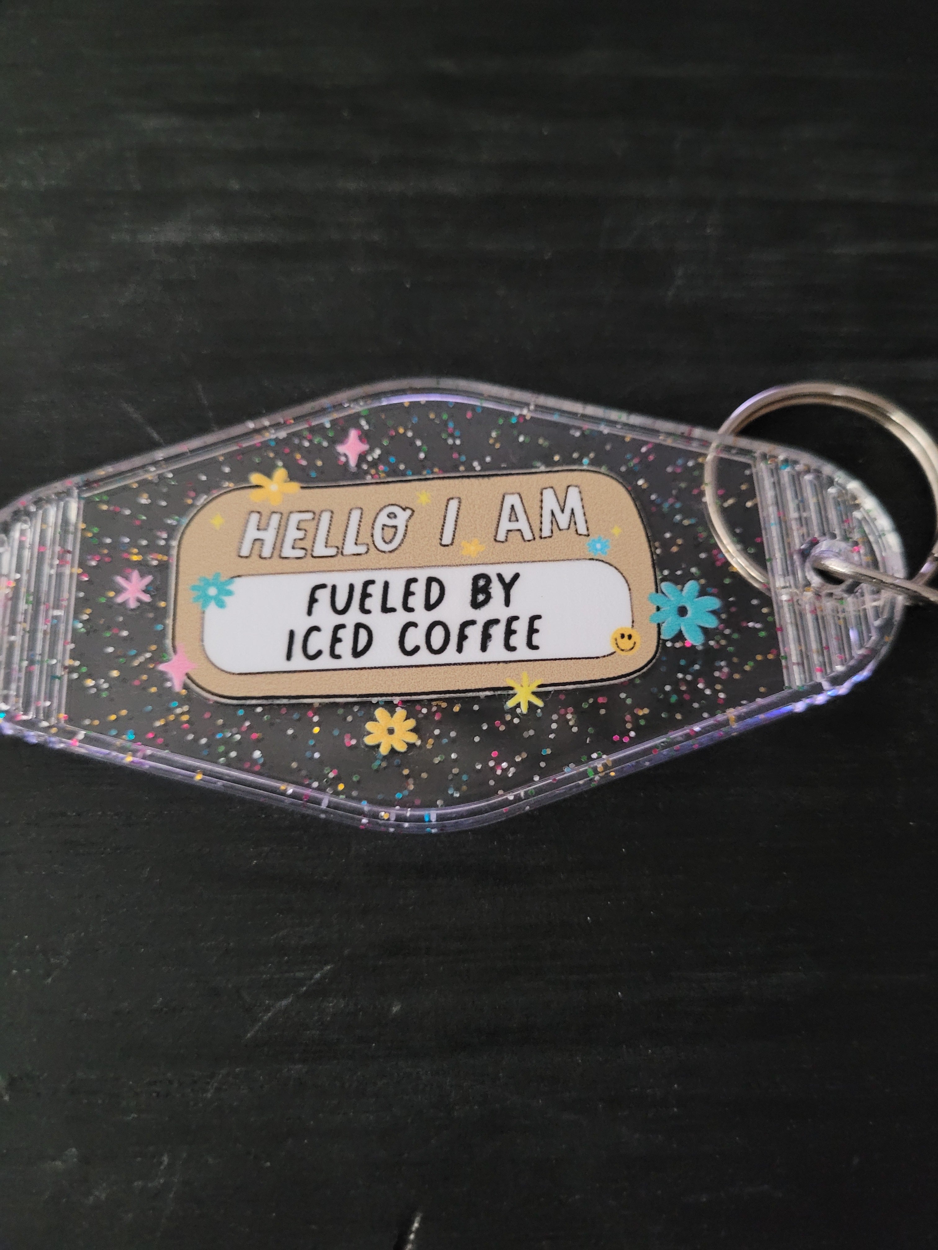Hello I Am Fueled By Iced Coffee black glitter motel-style keychain with colorful daisies and sparkle stars