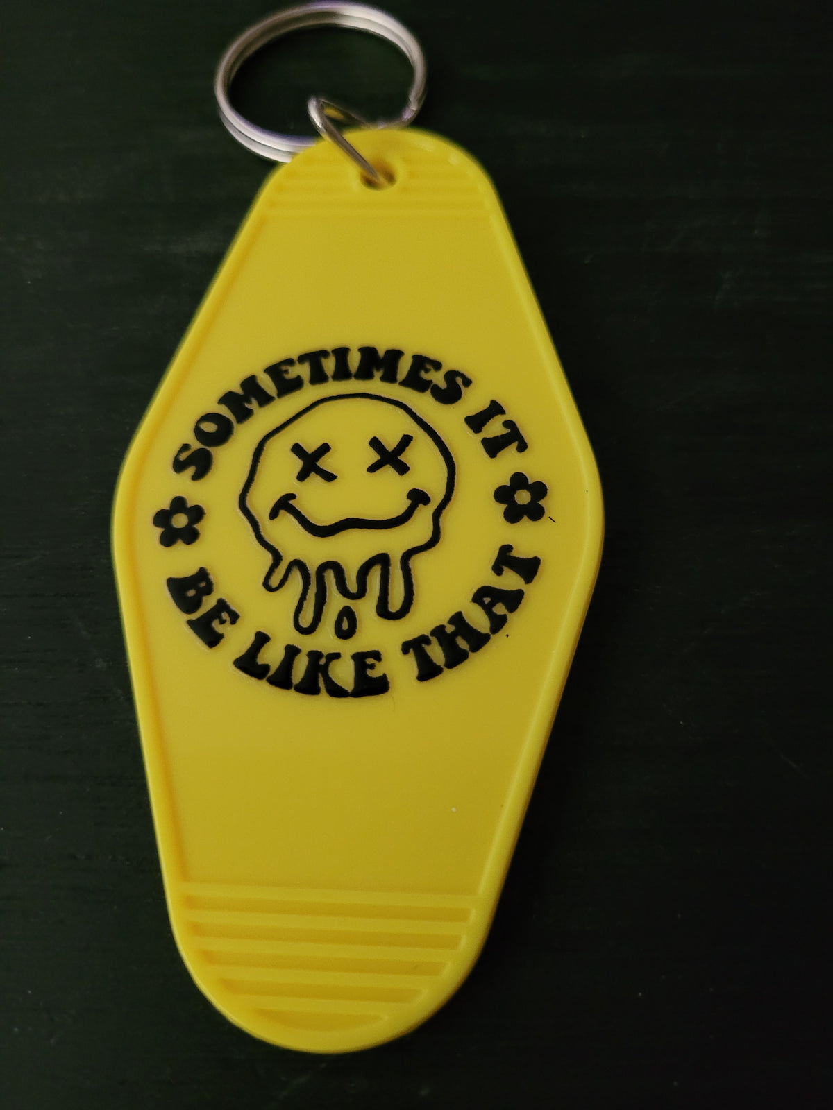 Sometimes It Be Like That bold yellow motel-style keychain with melting dizzy smiley face and flowers