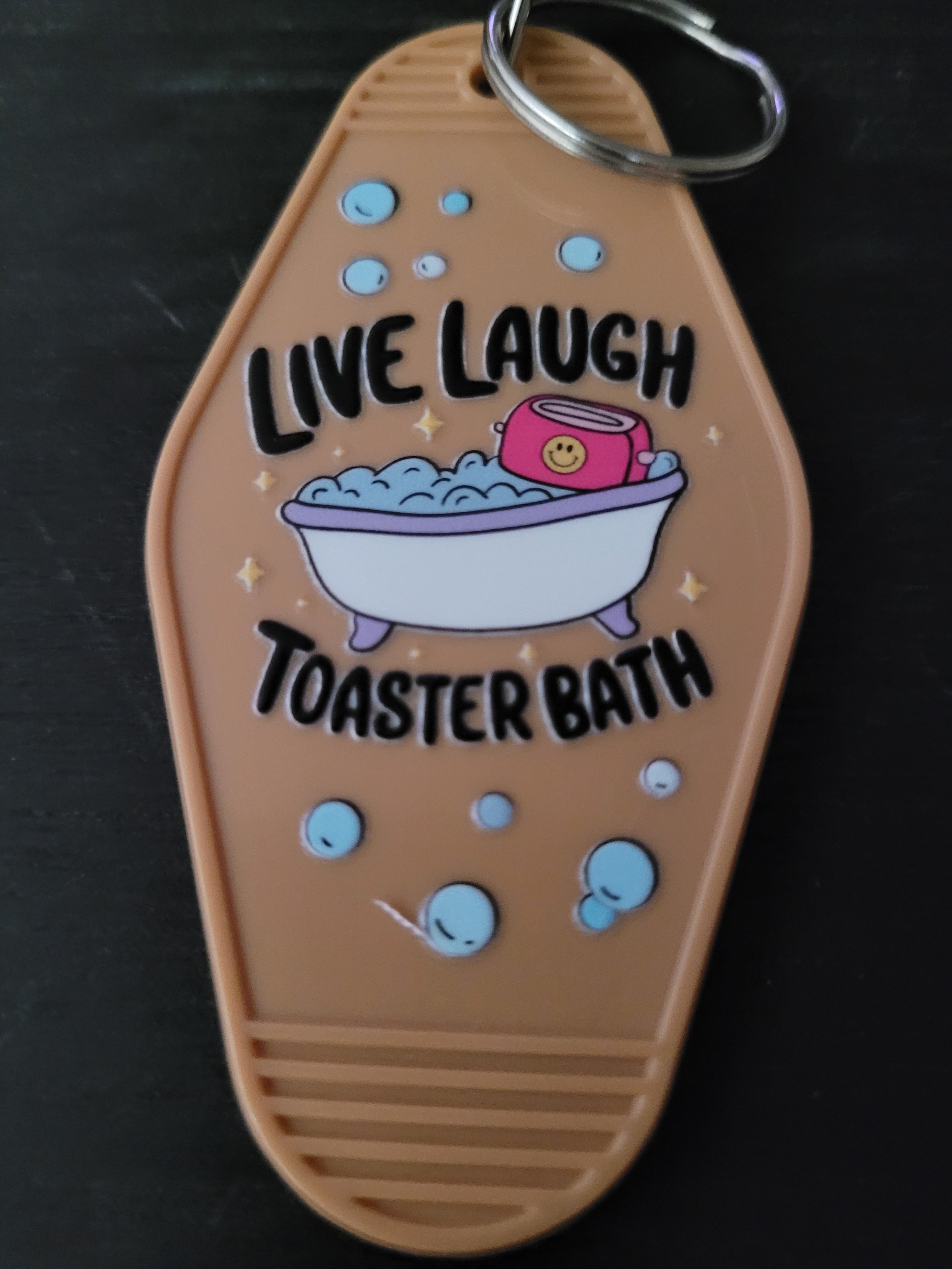 Live Laugh Toaster Bath tan motel-style keychain with bubbly bathtub and smiley toaster illustration