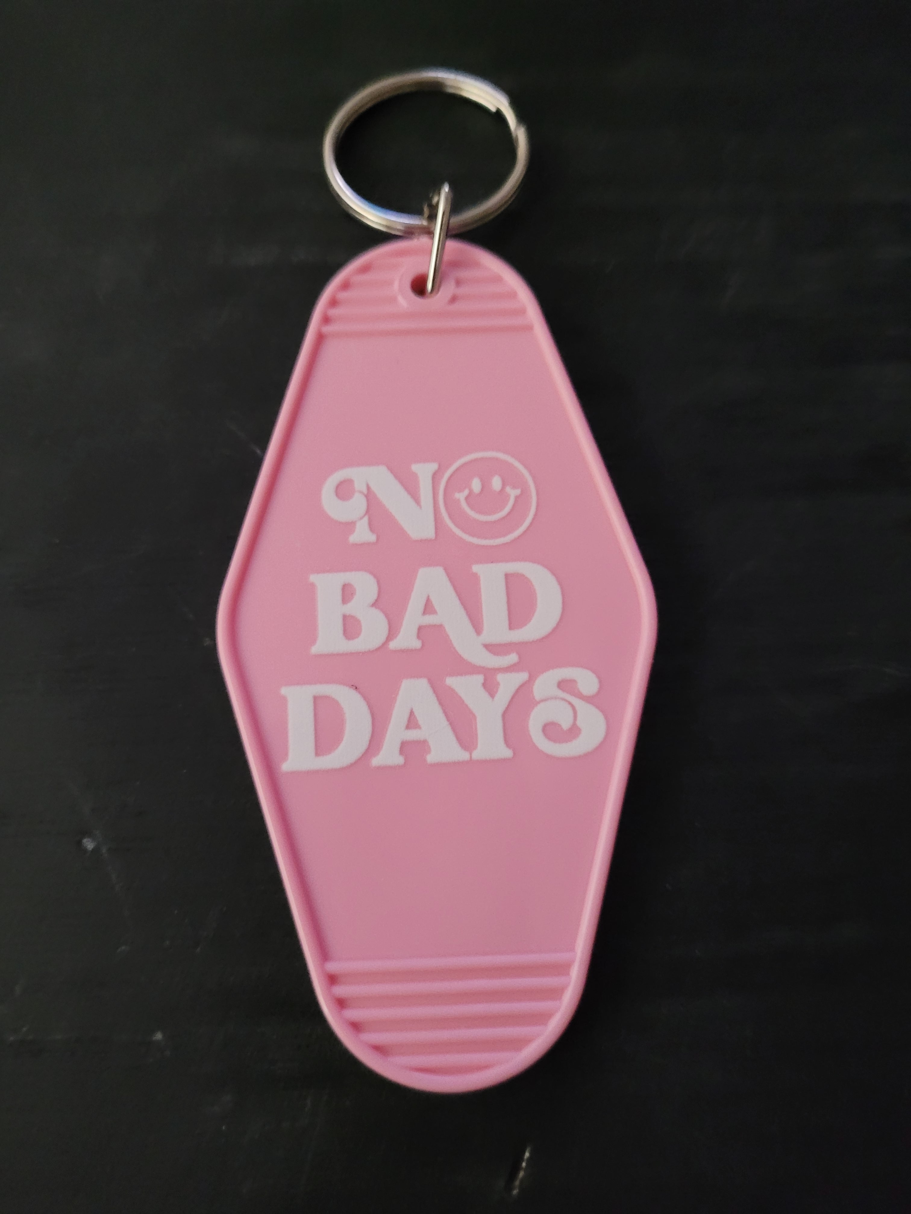 No Bad Days pink motel-style keychain with bold white lettering and smiley face in the O