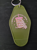 Running On Caffeine and Chaos olive green motel-style keychain with skeleton hand holding pink-lidded iced coffee and sparkle stars