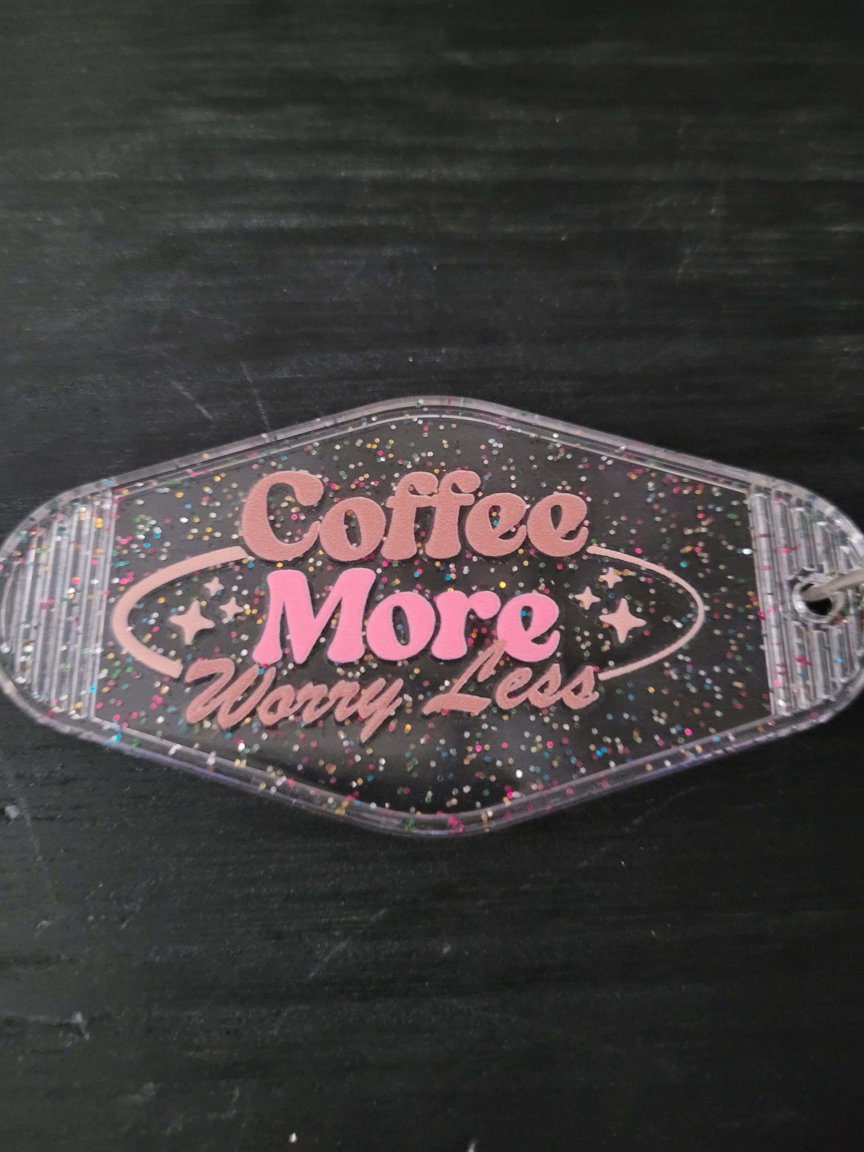 Coffee More Worry Less black rainbow glitter oval motel-style keychain with pink retro script lettering and sparkle star accents
