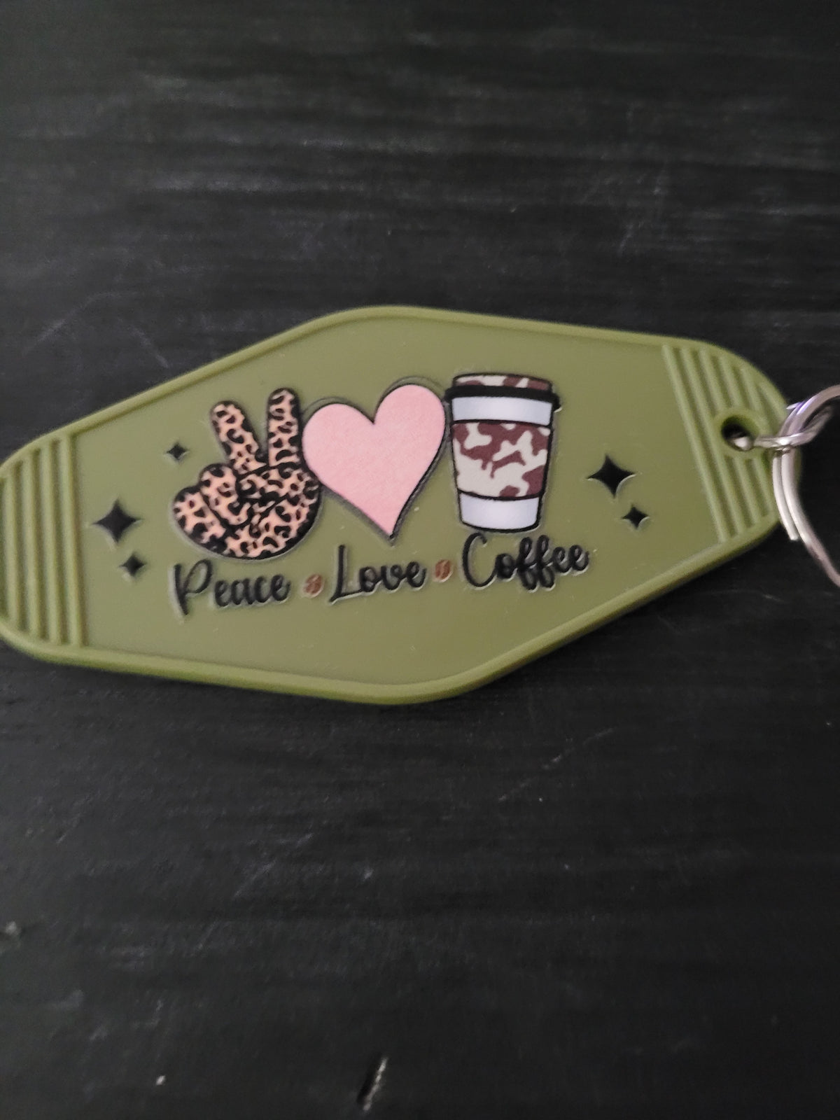 Peace Love Coffee olive green oval motel-style keychain with leopard print peace hand, pink heart, and cow print coffee cup illustrations