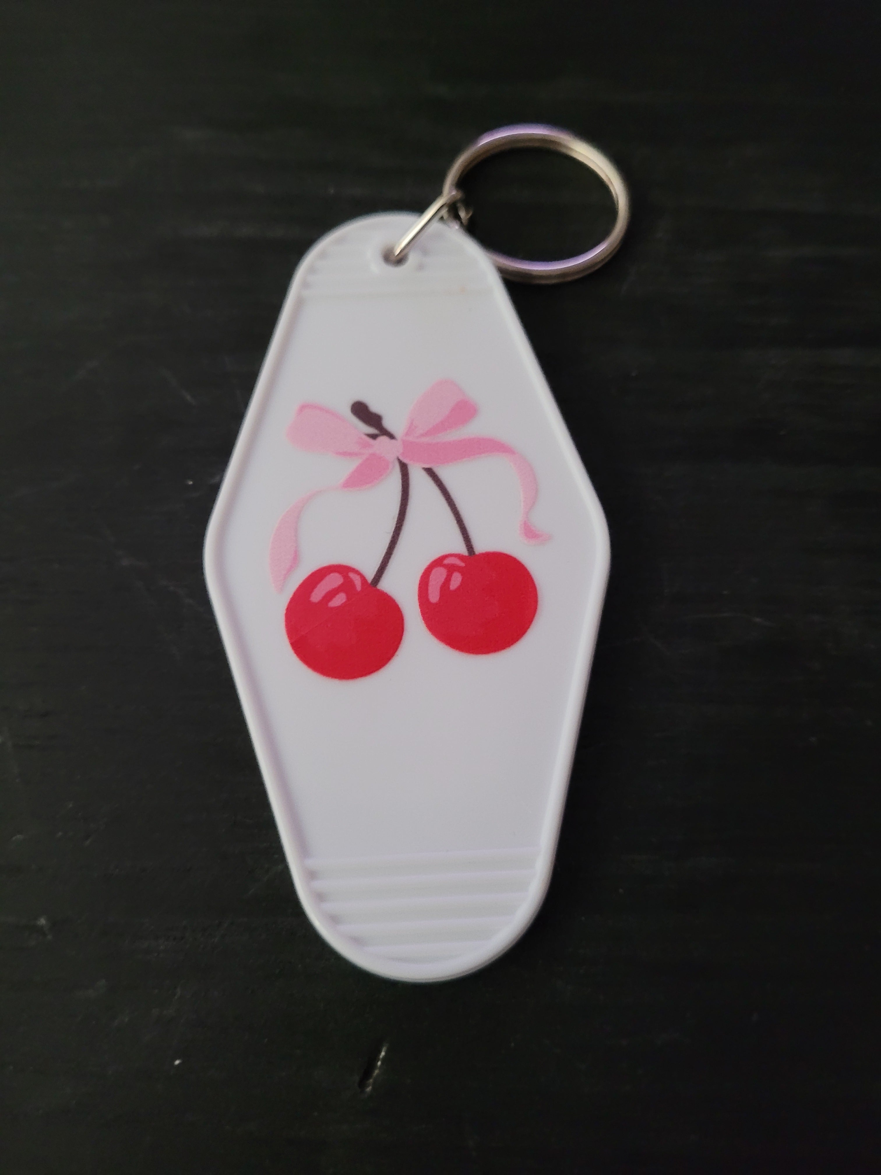 Cherry Bow white motel-style keychain with glossy red cherries tied with a soft pink bow illustration