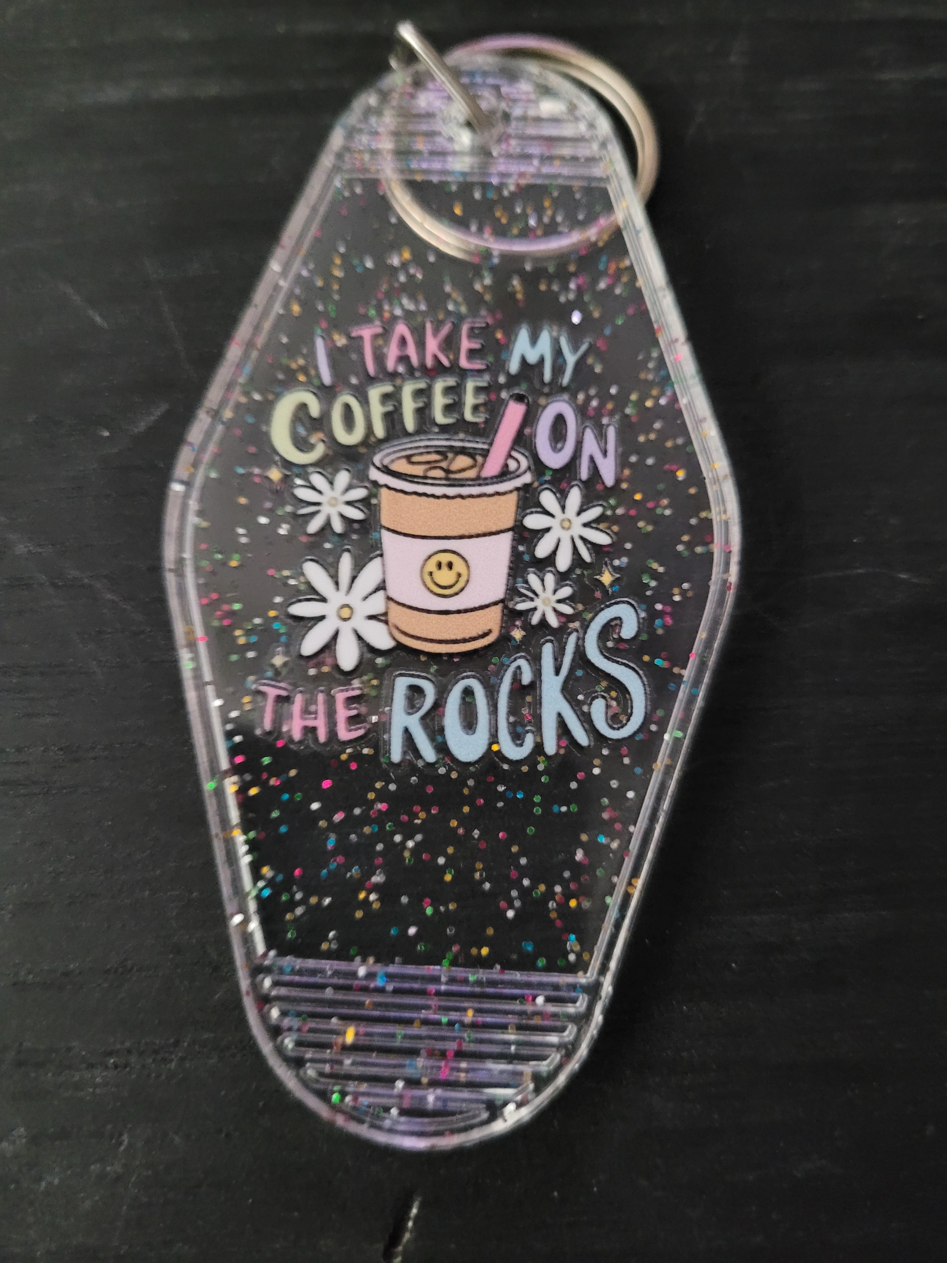 I Take My Coffee On The Rocks clear rainbow glitter motel-style keychain with smiley iced coffee cup and white daisy accents